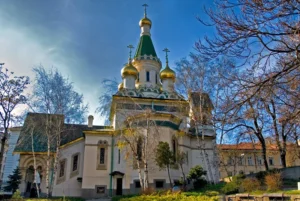 Руската църква в София (Свети Николай Чудотворец) – гледка откъм градинката с дървета и златни кубета 